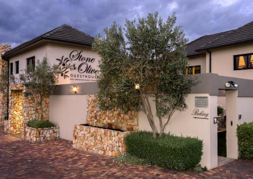 a house with a stone wall and a tree at Stone Olive in Jeffreys Bay