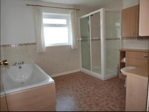 a bathroom with a tub and a shower and a sink at Ben Alder Spacious 3 Bedroom House in Orkney