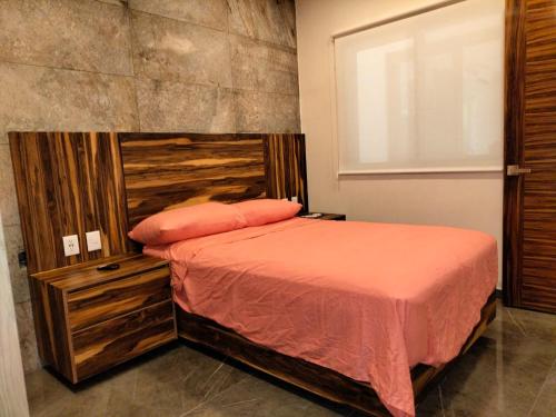 a bedroom with a bed with a wooden headboard at Condo arrosito village in Tangolunda