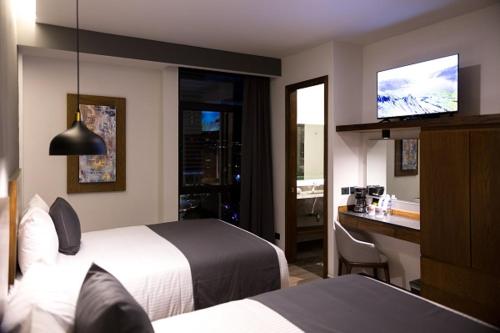 ein Hotelzimmer mit zwei Betten und einem Flachbildfernseher in der Unterkunft Gumont Guadalajara López Mateos - Minerva in Guadalajara