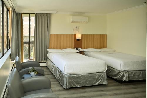 a hotel room with two beds and a chair at Hotel Opportune in Vancouver