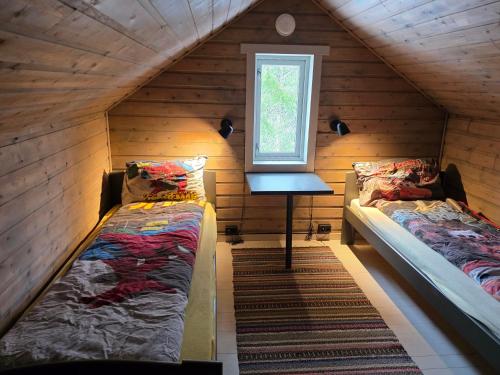 two beds in a wooden room with a window at Tronstadbu- 1800s Cabin near Geirangerfjord & Slogen Hike in Hellesylt