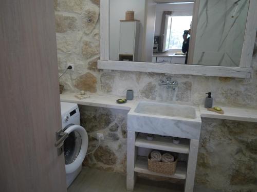 a bathroom with a sink and a mirror and a toilet at Private Villa Maothis in Corfu
