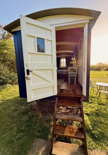 a tiny house with a door and a ladder at Shepherd's Hut near Oxford in Cumnor