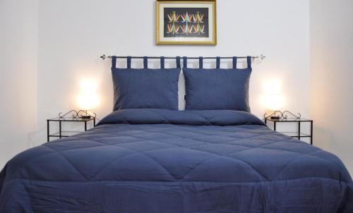 a bed with a blue comforter and two side tables at B&B Baroi Orgosolo in Orgosolo