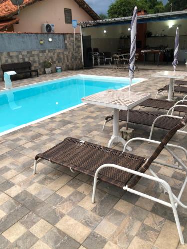 a swimming pool with chairs and a table and a table and a table at Casa da mãe joanna in Guapimirim
