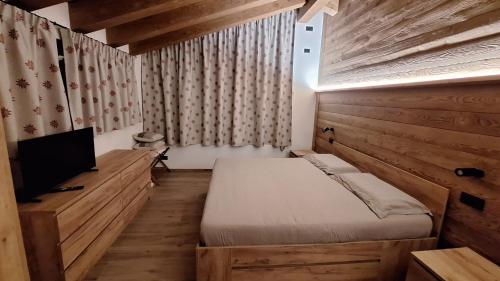 a bedroom with a bed and a flat screen tv at LA CASETTA - Appartamento CERVINO in Torgnon