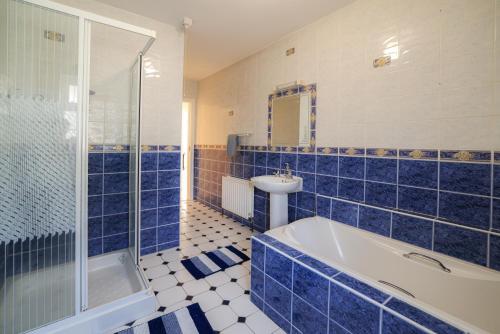 a blue tiled bathroom with a tub and a sink at Hillside House- Pine View in Ballinamuck
