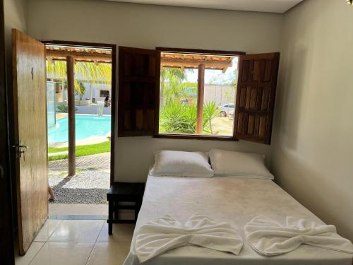 a bedroom with a bed and a view of a pool at Pousada Elizium in Montes Claros