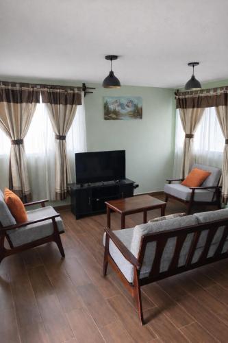 a living room with couches and a flat screen tv at Villa Ojo de Agua AIFA in Hacienda Ojo de Agua
