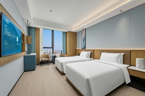 a hotel room with two beds and a projection screen at Fairfield by Marriott Yulin in Yulin