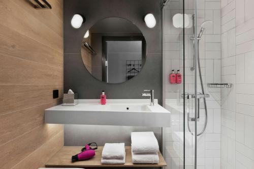 a bathroom with a sink and a mirror and a shower at Moxy Aarhus in Aarhus