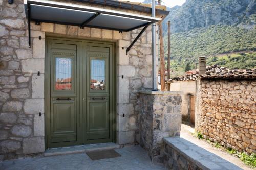 a green door on the side of a stone building at Achyronas 1840 Stone House in Graviá