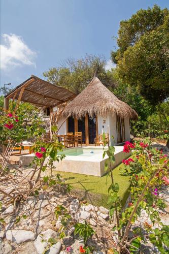 a small house with a thatch roof and a pool at AMALIFE Beach Club & Hotel in Tierra Bomba