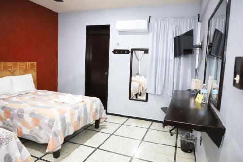 a bedroom with a bed and a table and a mirror at Hotel Murallas 231, CENTRO HISTORICO in Campeche