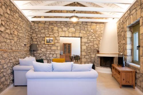 a living room with a white couch and a stone wall at Achyronas 1840 Stone House in Graviá