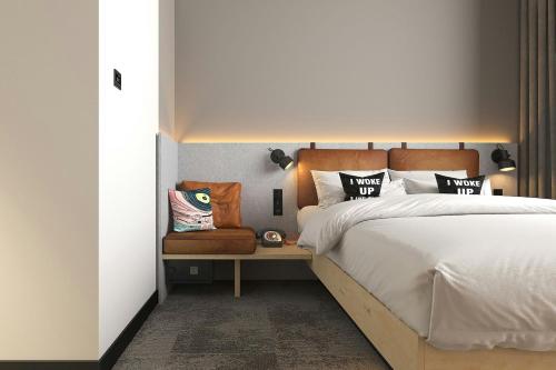 a bedroom with a large bed and a chair at Moxy Belgrade Skadarlija in Belgrade