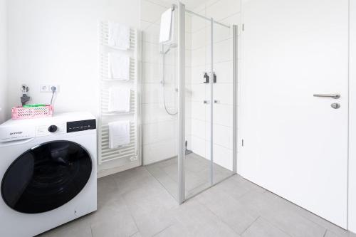 a washing machine in a white bathroom with a shower at Tonirooms 2 Zimmer Apartment Eisvogel in Straubing