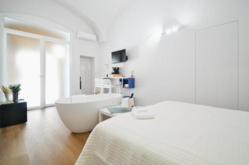 a white bedroom with a tub and a bed at Casa Lomè - Dimora Vacanze in Conversano