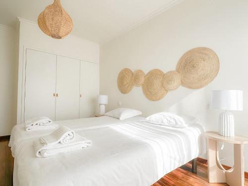 a white bedroom with a large bed with towels on it at Hello Esposende in Esposende