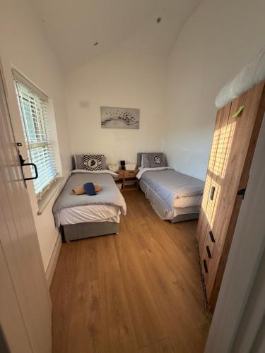 a room with two beds and a wooden floor at Beautiful Seaside Cottage Wicklow town in Wicklow