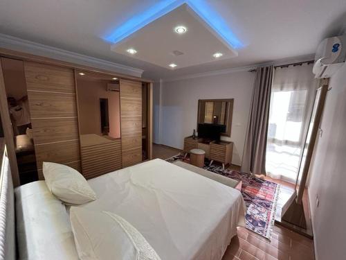 a bedroom with a large white bed and a television at Decent brand new flat with garden view in New cairo