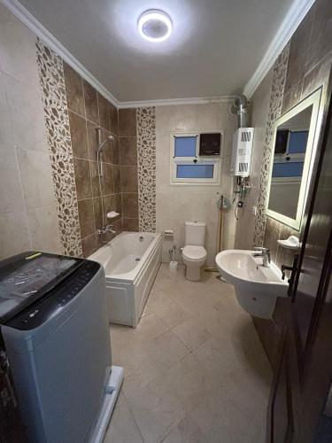 a bathroom with a tub and a toilet and a sink at Decent brand new flat with garden view in New cairo