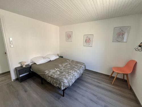 a bedroom with a bed and a orange chair at Maison de village in Collanges