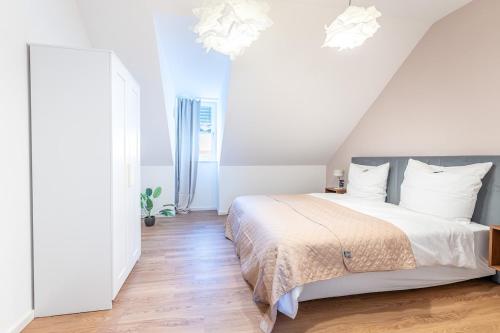 a bedroom with a bed with white walls and wooden floors at Tonirooms 3-Zimmer Buntspecht in Straubing