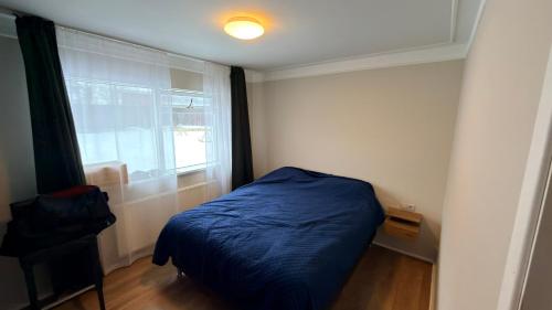 a bedroom with a blue bed and a window at Keflavik Heart in Keflavík