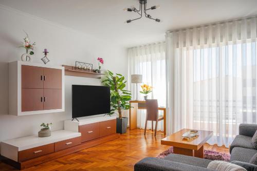 a living room with a couch and a tv at Garajau Terrace Apartment - Pool and Free Parking in Caniço
