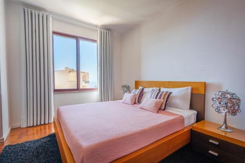 a bedroom with a large bed and a large window at Garajau Terrace Apartment - Pool and Free Parking in Caniço