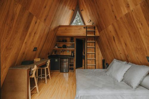 a bedroom with a bed and a kitchen in a cabin at WANDER CABINS Valle de Bravo in Valle de Bravo