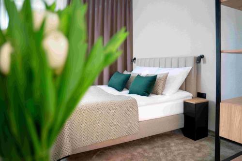a bedroom with a bed with green and white pillows at Villa Aria in Krynica Zdrój