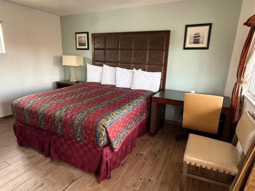 a hotel room with a bed and a desk and chair at Bayshore Inn Ventura in Ventura