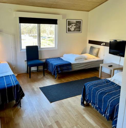 a bedroom with two beds and a chair and a window at Vätterledens Stugrum in Gränna