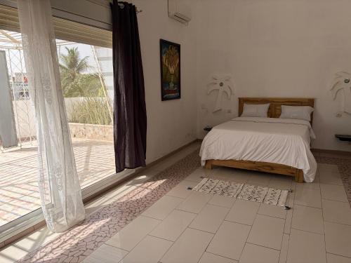 a bedroom with a bed and a large window at Luciana annexe in Mbour