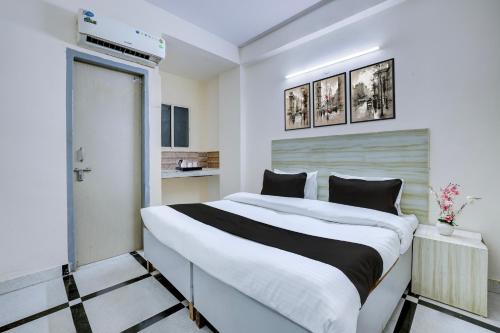 a bedroom with a large white bed with black pillows at Hotel O DLF Phase 1 Metro Station Gurugram in Gurgaon