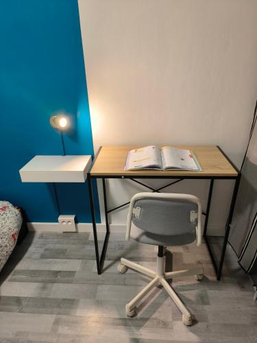 a desk with a chair and a book on it at Chambre spacieuse - appart sympa chez l'habitant in Saint-Herblain