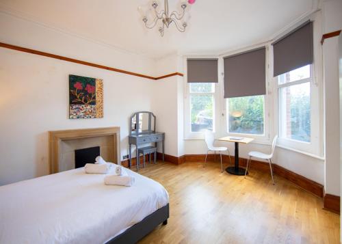 a bedroom with a bed and a desk and windows at Transvaal House Ely in Ely