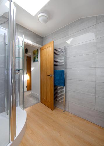 a bathroom with a shower and a wooden door at Transvaal House Ely in Ely