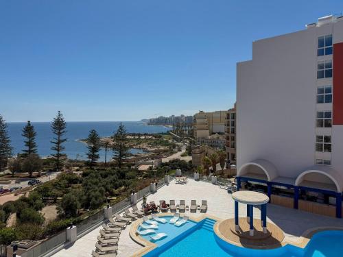 a view of a resort with a swimming pool and the ocean at Flamingo Apartments Malta in St. Julianʼs
