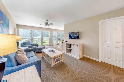 a living room with a blue couch and a table at Golf Course Condo with Pools & Family Fun in New Bern