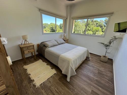 a bedroom with a bed and two windows at Casaquinta overlooking the golf course in Concepción del Uruguay