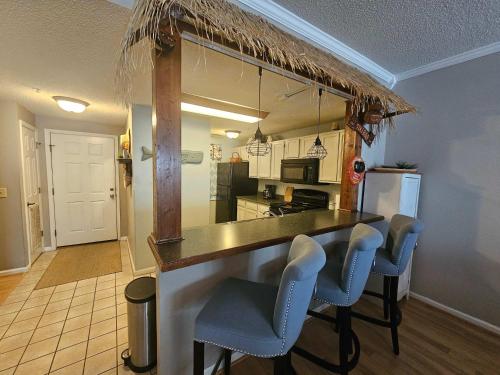 a kitchen with a bar with blue chairs in a room at Teal Lake 212 in North Myrtle Beach
