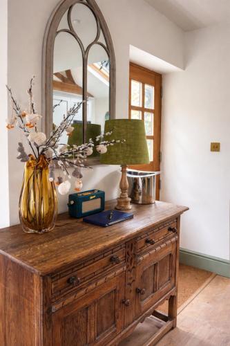 a wooden dresser with a lamp and a mirror on it at The little Hotel-luxury home in Motcombe