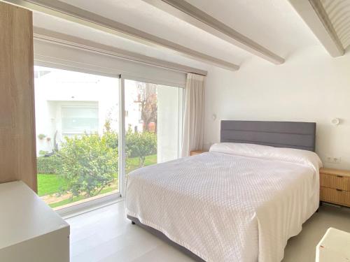 a bedroom with a bed and a large window at Precioso bungalow con piscina en 1a Linea Playa in Denia
