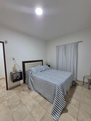 a bedroom with a bed with a striped blanket on it at Rincón del Sol en Albardón in Albardón