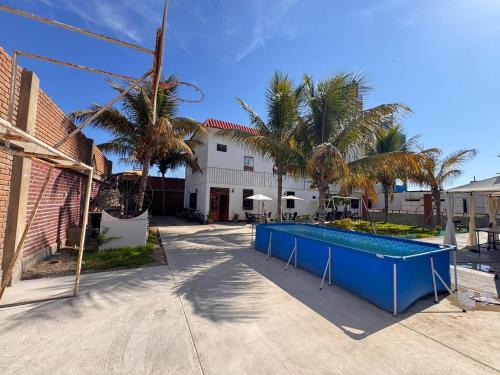 a swimming pool in front of a house with palm trees at La Arteza Pacasmayo in Pacasmayo