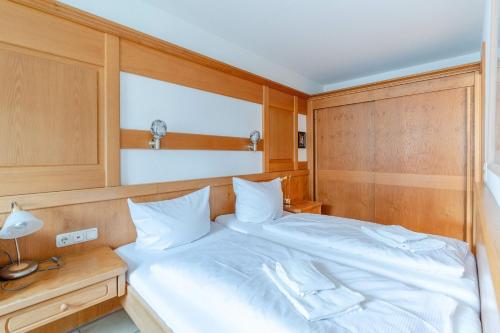 a bedroom with a white bed with a wooden headboard at Fewo Barth in Bad Hindelang